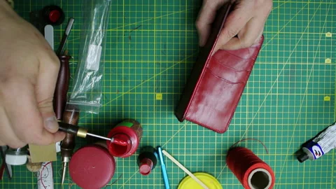 Applying paint to the edges red leather wallet DIY craft Stock-Footage 148049542