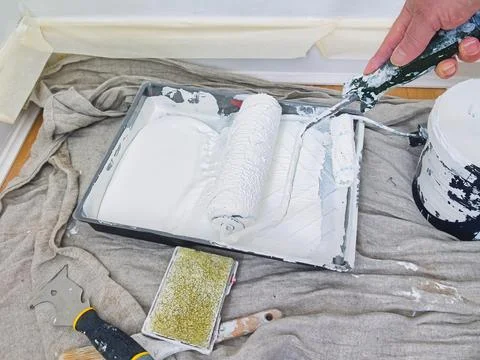 Applying paint to a paint roller in tray on floor ready for home renovation.. Stock Photos