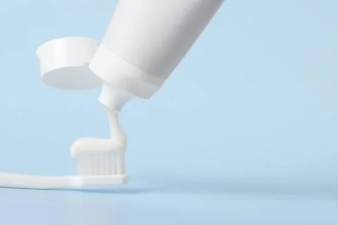 Applying paste on toothbrush against light blue background, space for text Foto stock