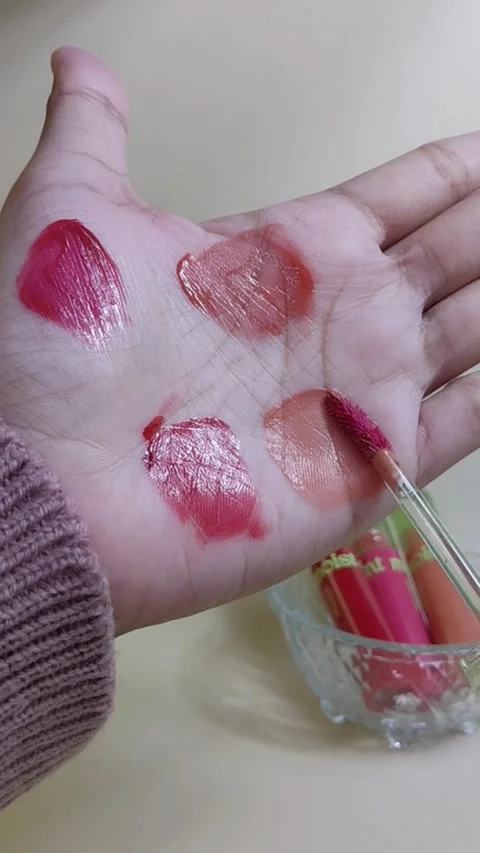 Applying pink lip tint on palm using brush applicator. Close up view. Lip c.. Stockbeeldmateriaal 338318667