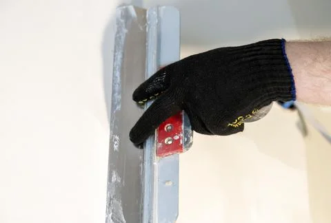 Applying plaster, plaster on the wall with a stainless steel spatula, close-up Stock Photos