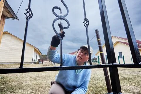 Applying protective coating to decorative elements of metal fence of entran.. Stock Photos