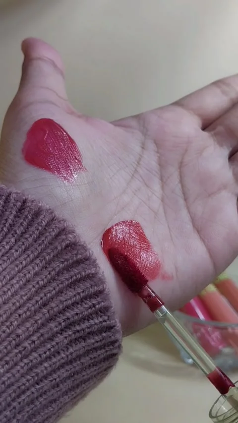 Applying red lip tint color on palm skin using brush applicator. Close up v.. Stock Footage 338318661