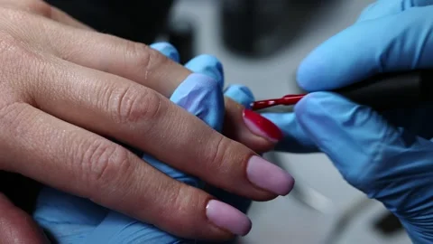 Applying Red Nail Polish in Beauty Salon, Close-up of a nail technician  Stock Footage 313229129