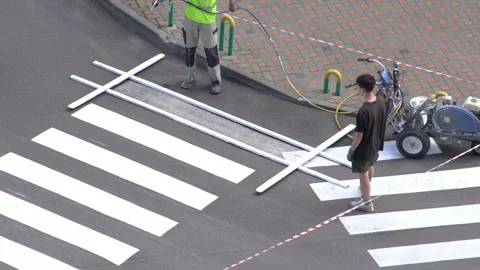 Applying road markings. Paint a pedestrian crossing with white paint Stock Footage 329966787