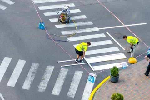 Applying road markings. Paint a pedestrian crossing with white paint. Stockfoto's
