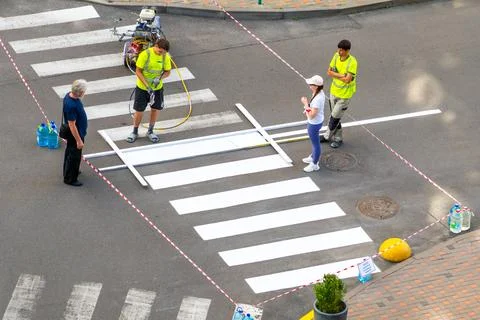 Applying road markings. Paint a pedestrian crossing with white color paint. H Stockfoto's