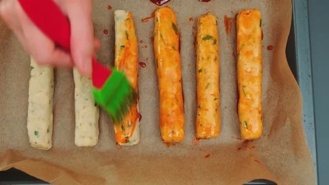 Applying Sauce to Raw Sausage Logs on Baking Sheet in Kitchen Stock Footage 342872248