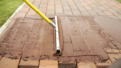 Applying sealant to a paver brick patio with a squeegee tool Stock Footage 322975226