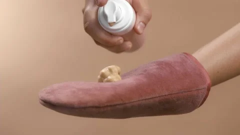 Applying self-tanner mousse to a rose massage glove. ready to use. High quality Video stock 157427191
