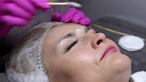 Applying shampoo for eyebrows and eyelashes of the model with a brush in a beaut Stock Footage 156236891