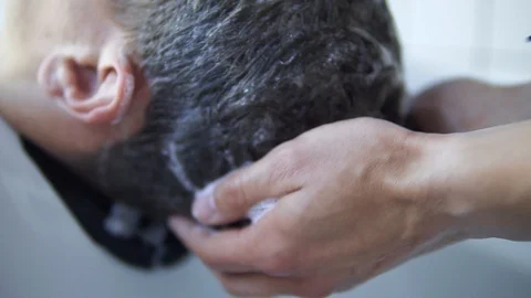 Applying shampoo to male head inside the sink at hairdresser salon Stock Footage 107832188