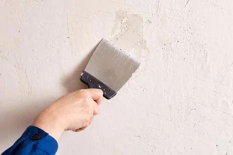 Applying skim plaster to wall with help of putty knife. Stock Photos