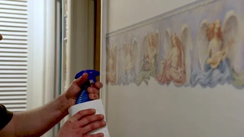 Applying a spray solution to soften the wallpaper border for easy removal Stock Footage 306226302