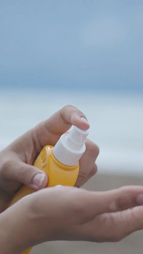 Applying sunscreen at the beach during daytime hours 库存影片 335564508