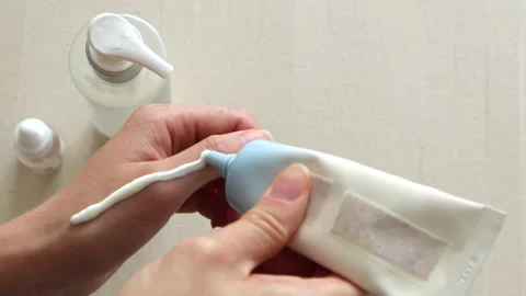 Applying sunscreen or moisturizer cream to female hand. Beige minimal and c.. Vídeos de archivo 316702896