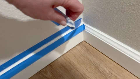 Applying Tape Along Baseboard Edge Stock Footage 323518769