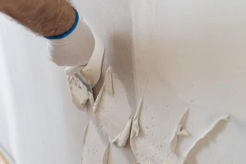 Applying textured plaster to wall surface with precision by construction Stock Photos