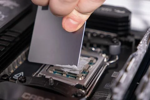 Applying thermal paste to cpu with precision tool, close-up on processor surf 写真素材