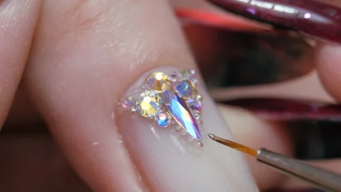 Applying a three-dimensional pattern with rhinestones and broths on the nail. Stock Footage 211476204