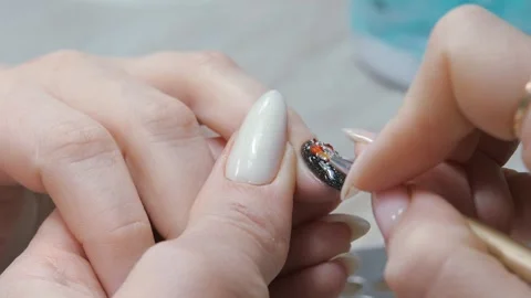 Applying a three-dimensional pattern with rhinestones and broths on the nail. Stock Footage 282740737