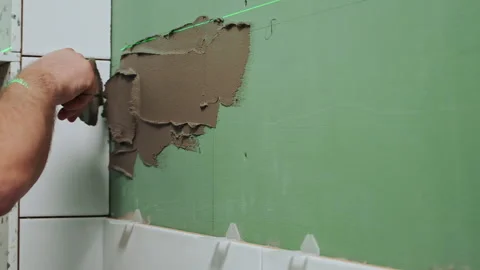 Applying tile adhesive to the bathroom wall by the hands of an unrecognizable Stock Footage 195504883