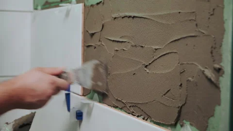 Applying tile adhesive to the bathroom wall by the hands of an unrecognizable Video stock 195509070