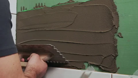 Applying tile adhesive to the bathroom wall by the hands of an unrecognizable Stock Footage 206863292