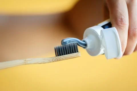 Applying toothpaste on a bamboo tooth brush. Stock Photos