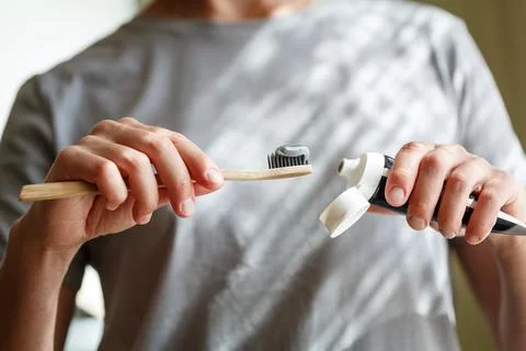 Applying toothpaste on a bamboo tooth brush. Hands squeezing tube with a to.. Stock Photos