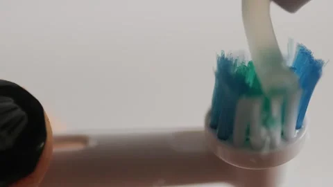 Applying toothpaste to electric toothbrush head close up 스톡 동영상 329222765