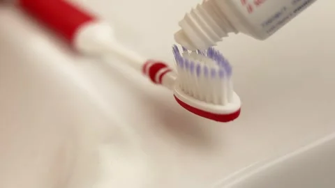 Applying toothpaste on red toothbrush closeup shot Stock Footage 318849697