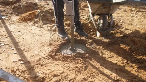Applying vibration to settle wet concrete properly, worker uses handheld Stock Footage 319691133