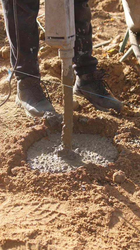 Applying vibration to settle wet concrete properly, worker uses handheld Stock Footage 319704577