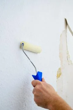 Applying wallpaper paste with a roller to prepare for new wallpaper Stock Photos