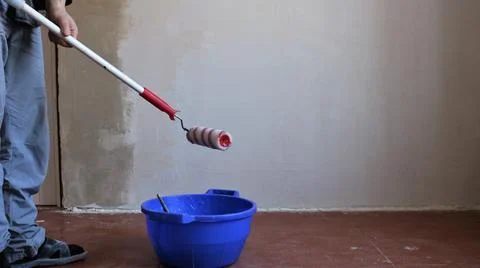 Applying wallpaper paste to the wall with a roller on a long handle Stock Photos