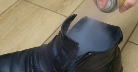 Applying Waterproof Spray to Black Leather Boot on Wooden Floor Stock Footage 323584424