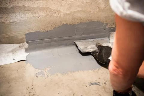Applying a waterproofing tape to the joint between the wall and the floor Stock Photos
