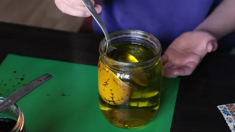 Applying a wax pattern on an Easter egg. The girl paints it yellow. 4K video Stock Footage 234709460