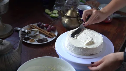 Applying white cream over a layered cake Stock Footage 153876834