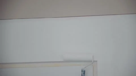 Applying white paint to the wall with a special roller. Painting during ren.. Stock Footage 246037473