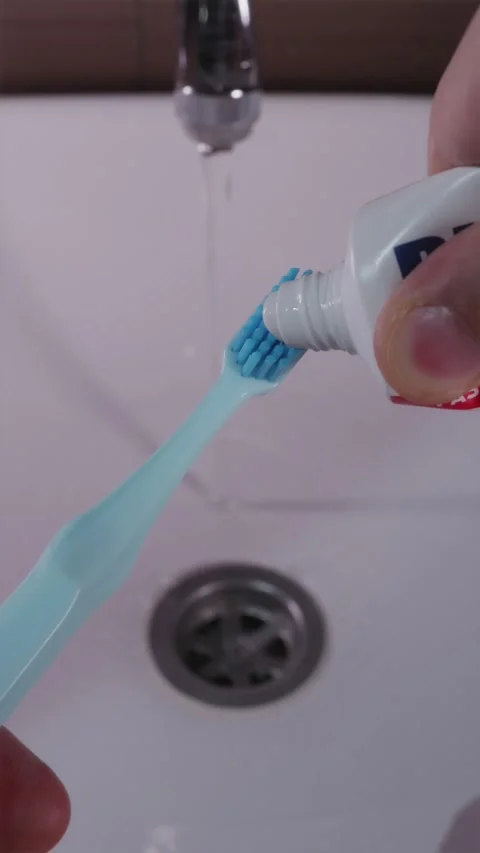 Applying white toothpaste onto blue toothbrush bristles close up Stock-Footage 344876982