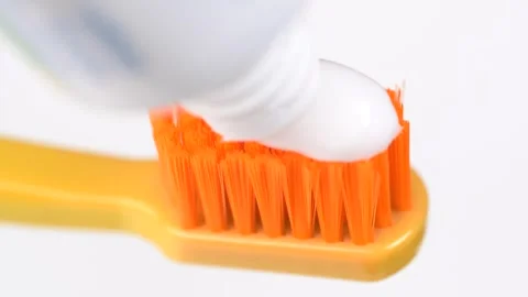 Applying white toothpaste to a orange toothbrush macro video. Dental care c.. Stock Footage 278689081