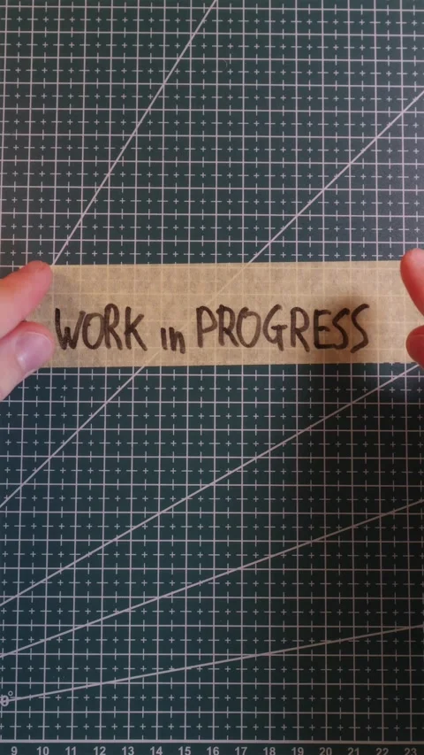 Applying WORK IN PROGRESS tape sticker on green mat. Stock Footage 337816351