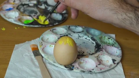 Applying Yellow Paint to Top of Easter Egg on Palette Stock Footage 329248200