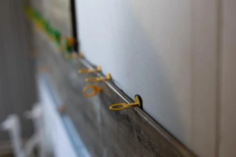 Applying yellow tile leveling clips between new floor tiles and a wall to ensure Stock Photos