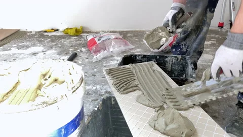 Applyng cement adhesive on ceramic tile - Installing ceramic floor tiles. Stock-Footage 153537575