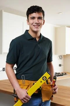 Apprentice Carpenter Installing Luxury Fitted Kitchen 스톡 사진