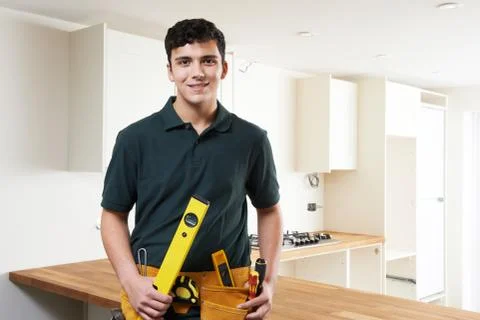 Apprentice Carpenter Installing Luxury Fitted Kitchen Stock Photos