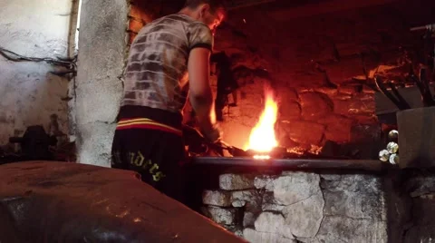 Apprentice Checks Using Forceps Readiness Iron Billet in an Ancient Smithy in Video stock 59762682